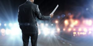 Back view of businessman speaker standing on podium in lights
